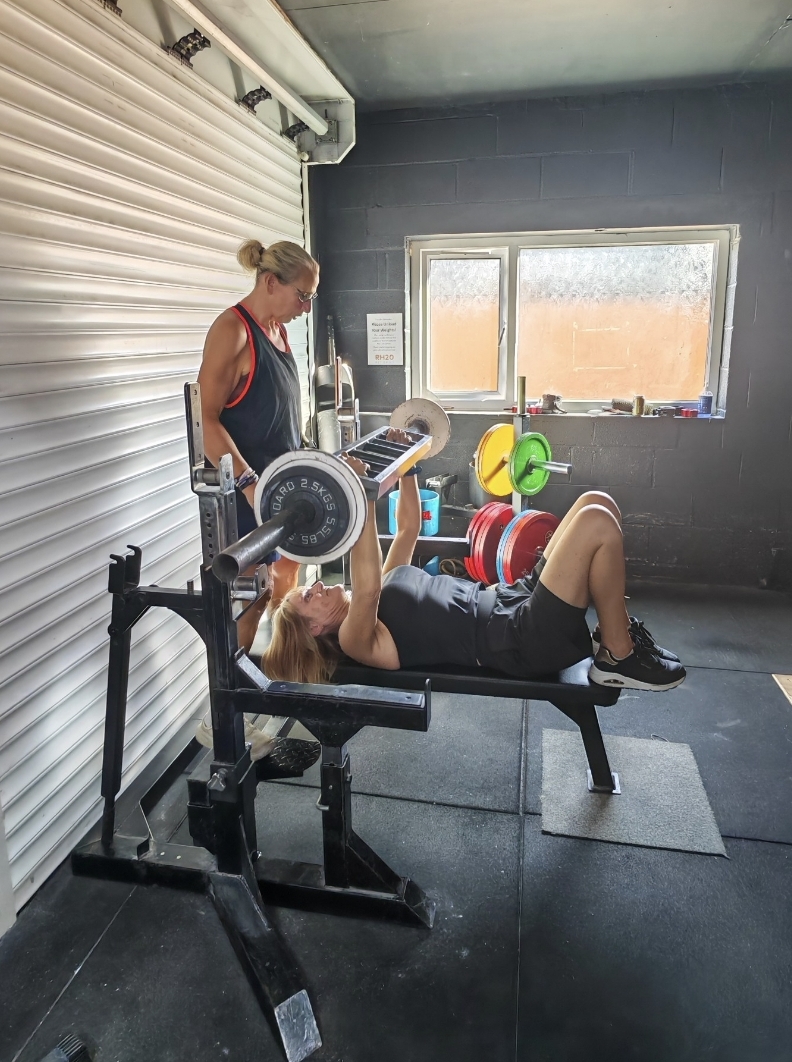 Emma supporting a client during a bench press